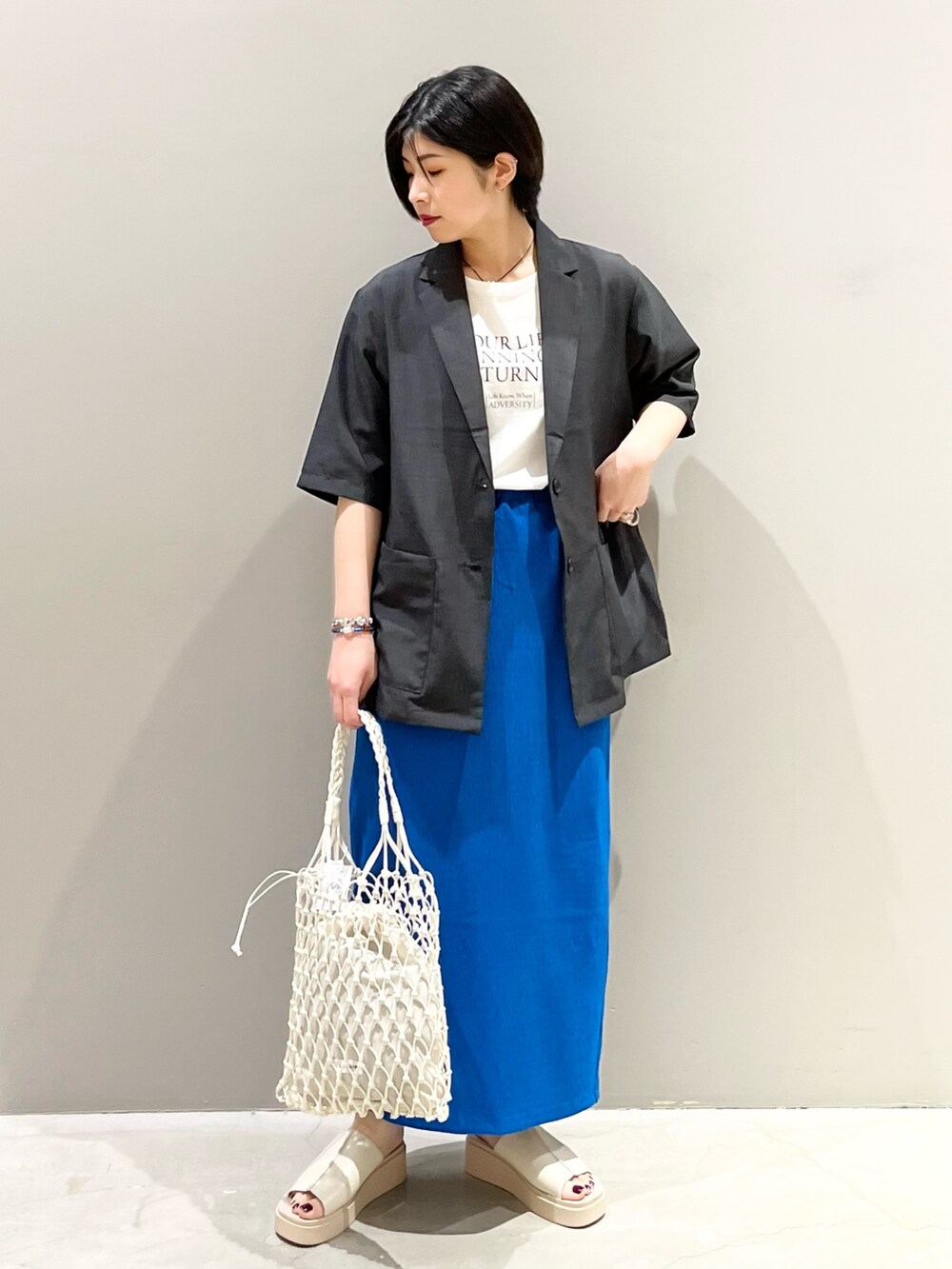 ブルー系のスカート、ホワイト系のトートバッグ、ベージュ系のサンダルを着用したレディースの夏コーディネートの2枚目の写真