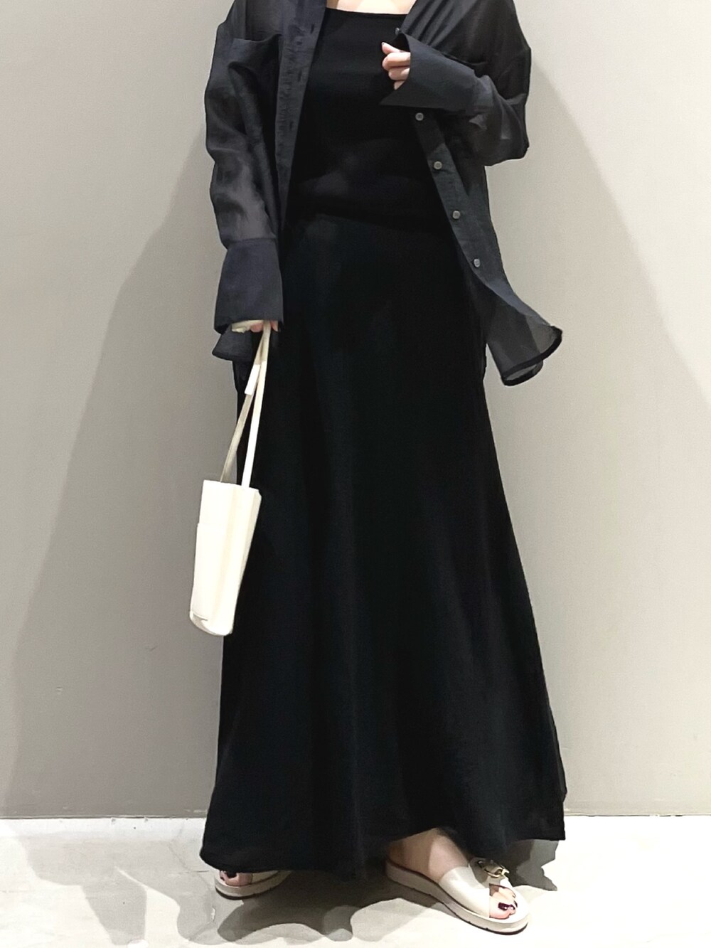 ホワイト系のサンダル、オレンジ系のバッグ、ブラック系のスカートを着用したレディースの夏コーディネートの6枚目の写真