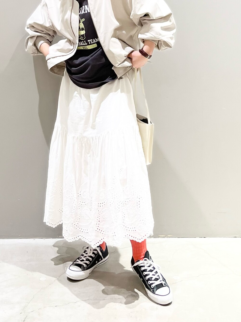 ブラック系のスニーカー、ホワイト系のスカート、ホワイト系のショルダーバッグを着用したレディースの春コーディネートの2枚目の写真