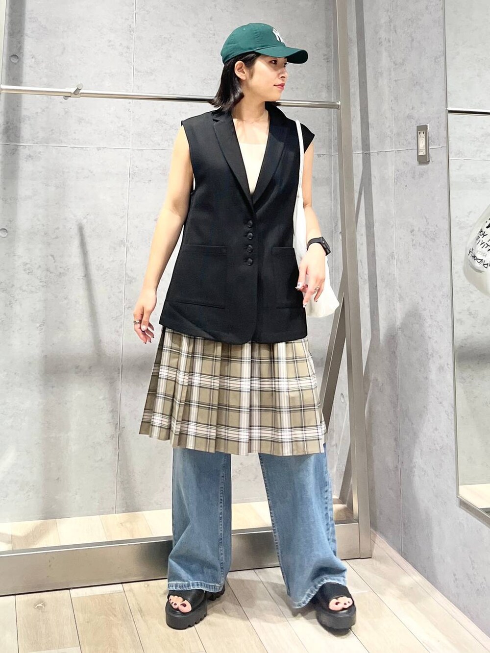 ホワイト系のタンクトップ、ブラック系のサンダル、ベージュ系のスカートを着用したレディースの秋コーディネートの2枚目の写真