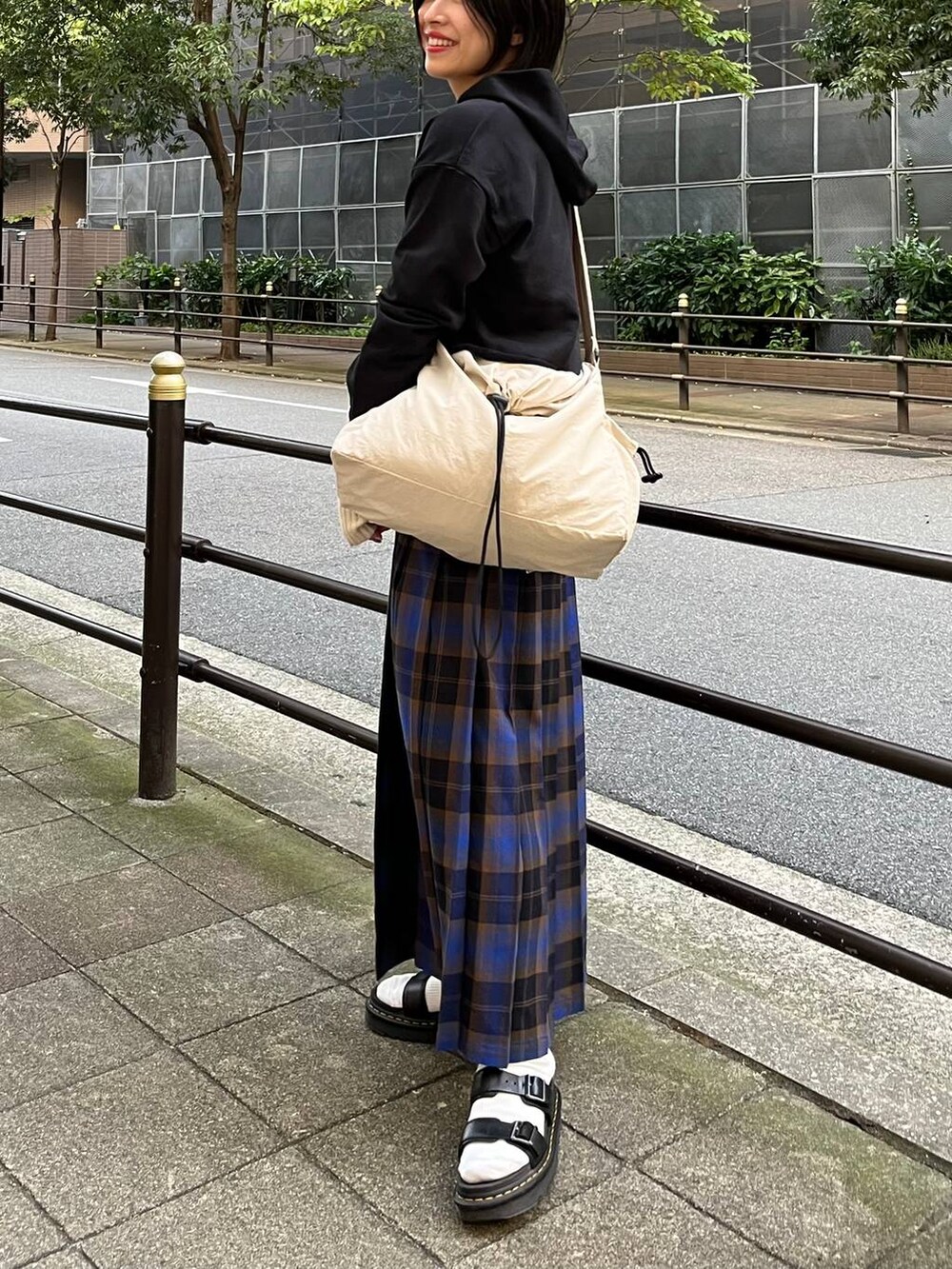 ブラック系のパーカー、ブルー系のスカート、ホワイト系のショルダーバッグを着用したレディースの秋コーディネートの4枚目の写真