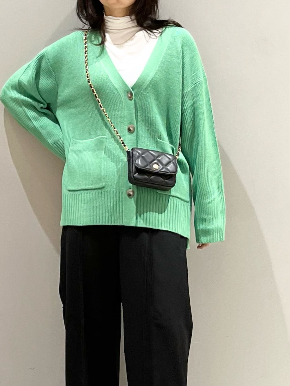 ブラック系のブーツ、ブラック系のスラックス、ブラック系のショルダーバッグを着用したレディースの秋コーディネートの2枚目の写真