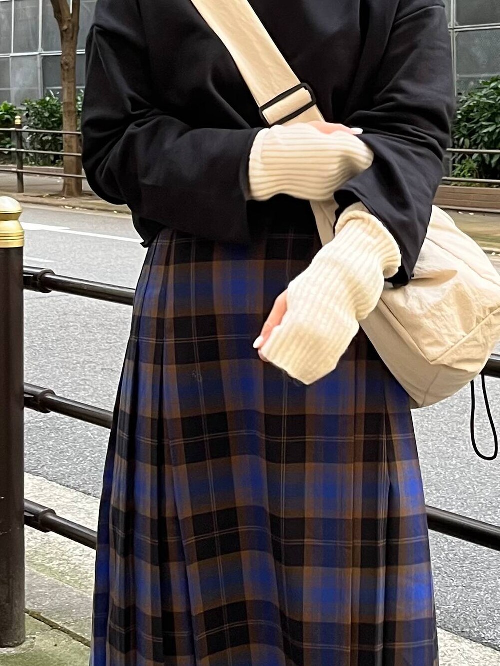 ブラック系のパーカー、ブルー系のスカート、ホワイト系のショルダーバッグを着用したレディースの秋コーディネートの7枚目の写真