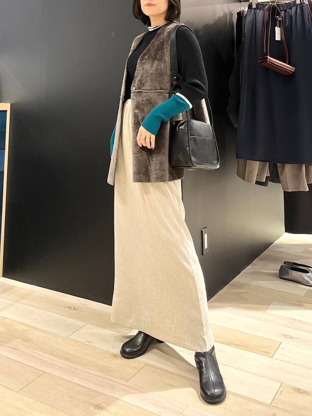 ブラック系のニット/セーター、ブラック系のブーツ、ブラック系のショルダーバッグを着用したレディースの秋コーディネートの6枚目の写真