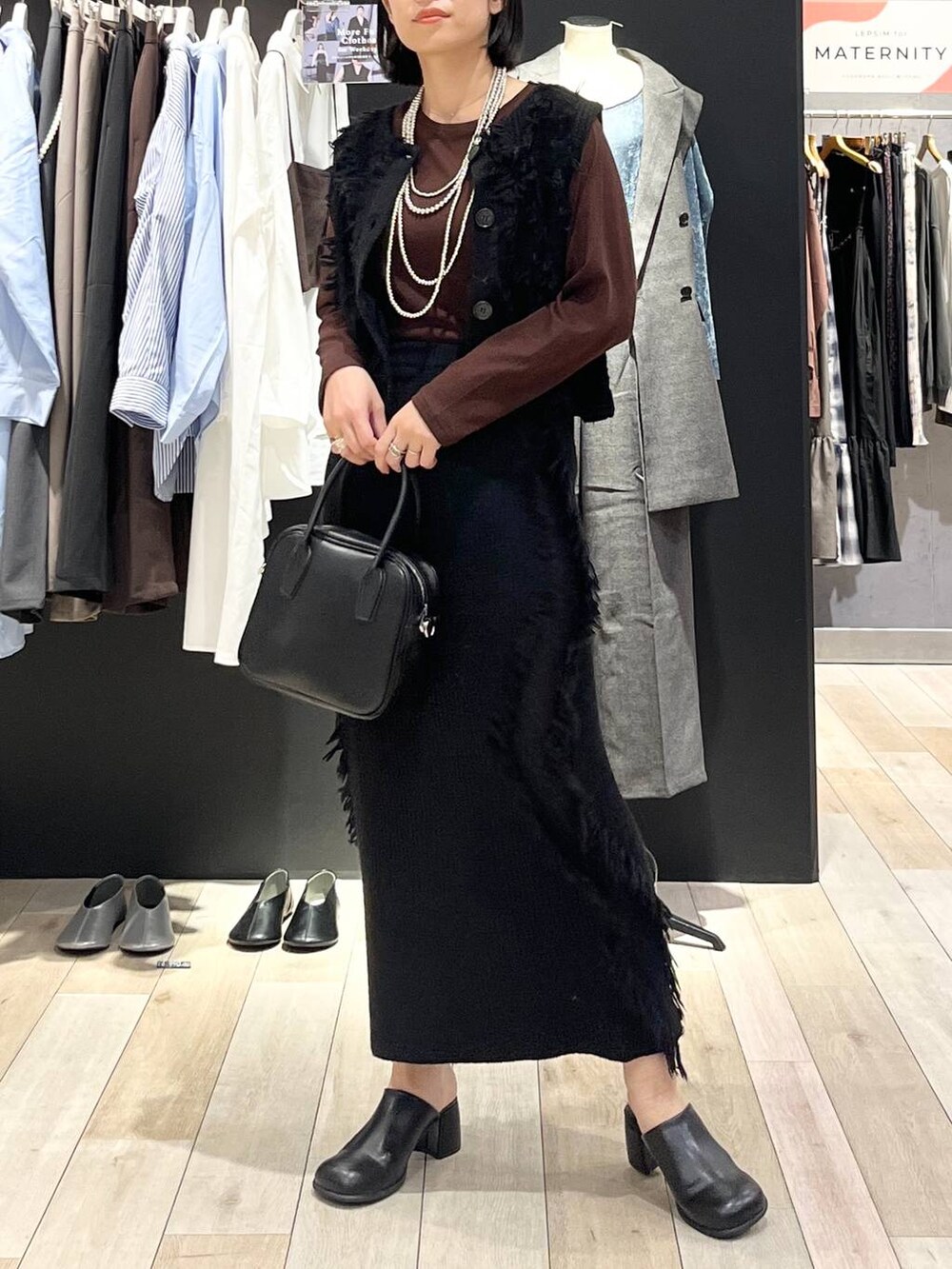 ブラック系のその他シューズ、ブラック系のボストンバッグ、ブラウン系のTシャツ/カットソーを着用したレディースの秋コーディネートの2枚目の写真