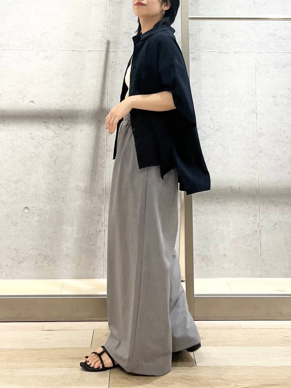 ブラック系のサンダル、ブラック系のハンドバッグ、ホワイト系のタンクトップを着用したレディースの夏コーディネートの6枚目の写真