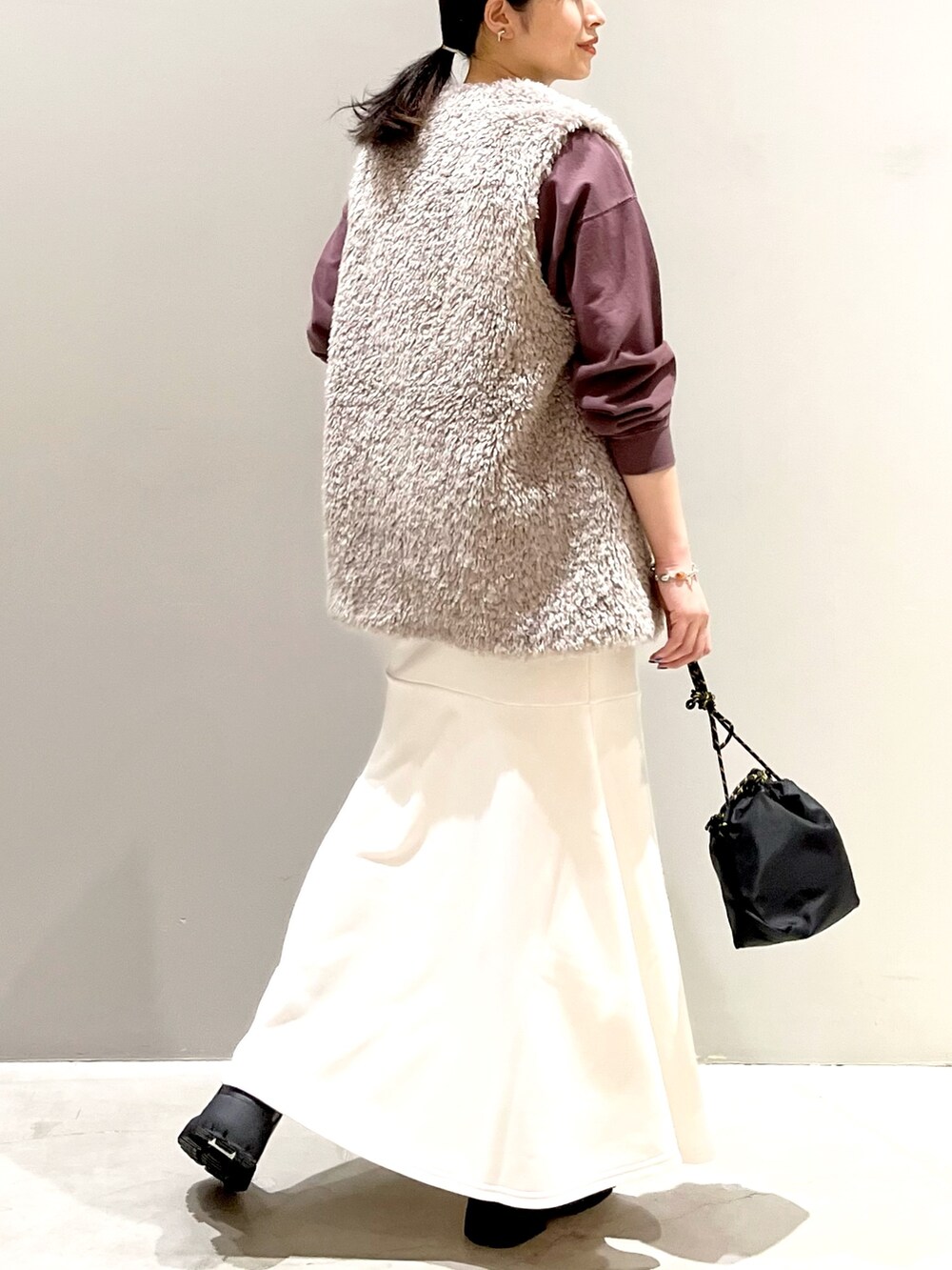 ホワイト系のスカート、ブラック系のブーツ、ブラック系のショルダーバッグを着用したレディースの秋コーディネートの3枚目の写真