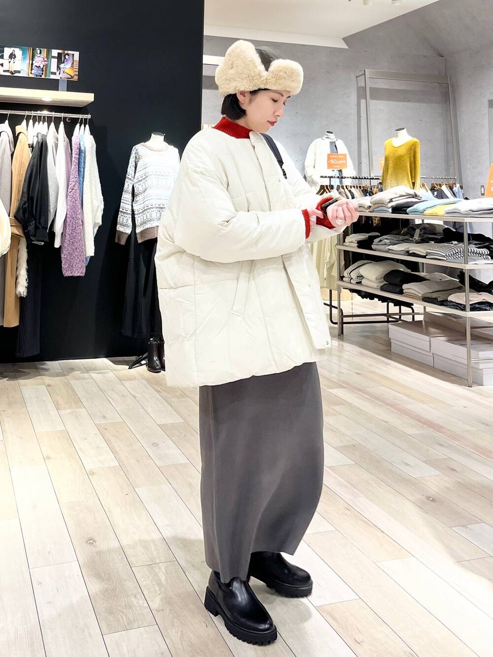 レッド系のニット/セーター、グレー系のスカート、ブラック系のブーツを着用したレディースの冬コーディネートの2枚目の写真