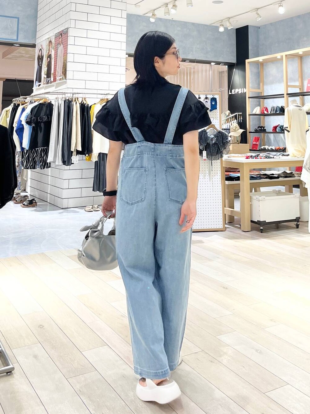 ホワイト系のサンダル、ブルー系のデニムパンツ、シルバー系のショルダーバッグを着用したレディースの夏コーディネートの4枚目の写真