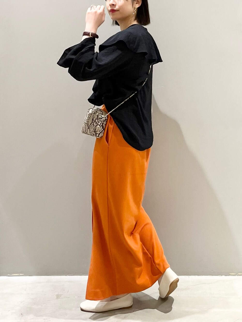 オレンジ系のスカート、ホワイト系のパンプス、その他のショルダーバッグを着用したレディースの春コーディネートの5枚目の写真