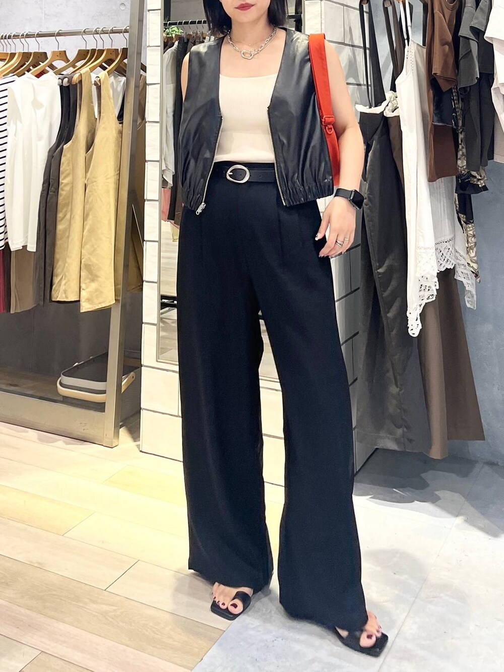 ホワイト系のタンクトップ、ブラック系のその他パンツ、オレンジ系のショルダーバッグを着用したレディースの夏コーディネートの2枚目の写真