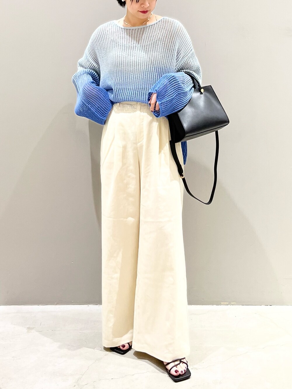 ブルー系のニット/セーター、ブラック系のショルダーバッグ、ブラック系のサンダルを着用したレディースの春コーディネートの7枚目の写真