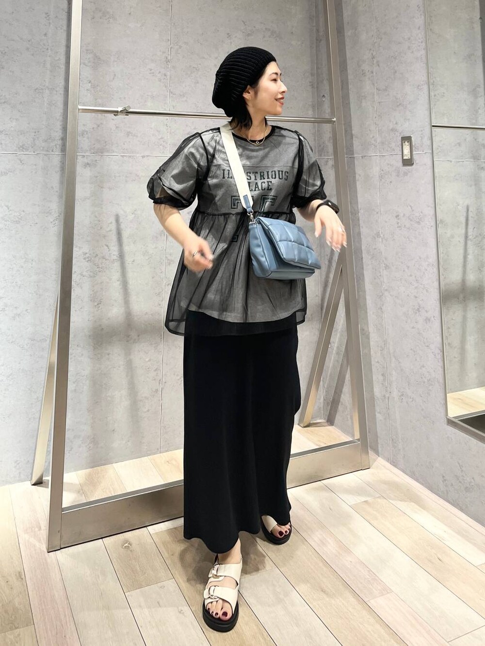 ブルー系のショルダーバッグ、ブラック系のスカート、ホワイト系のサンダルを着用したレディースの春コーディネートの5枚目の写真