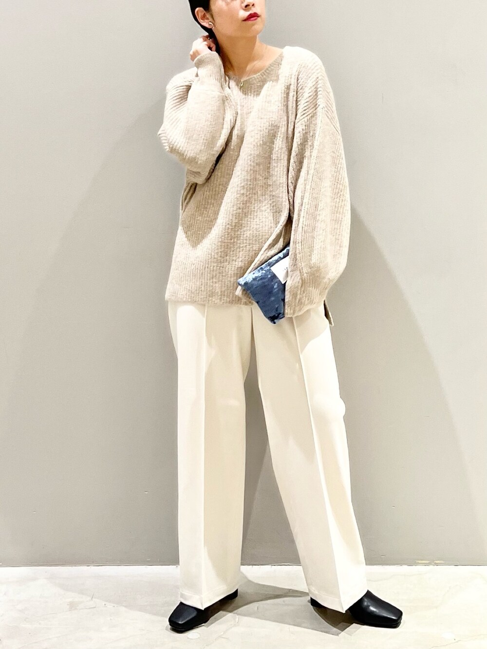 ベージュ系のニット/セーター、ホワイト系のスラックス、ブラック系のブーツを着用したレディースの秋コーディネートの5枚目の写真