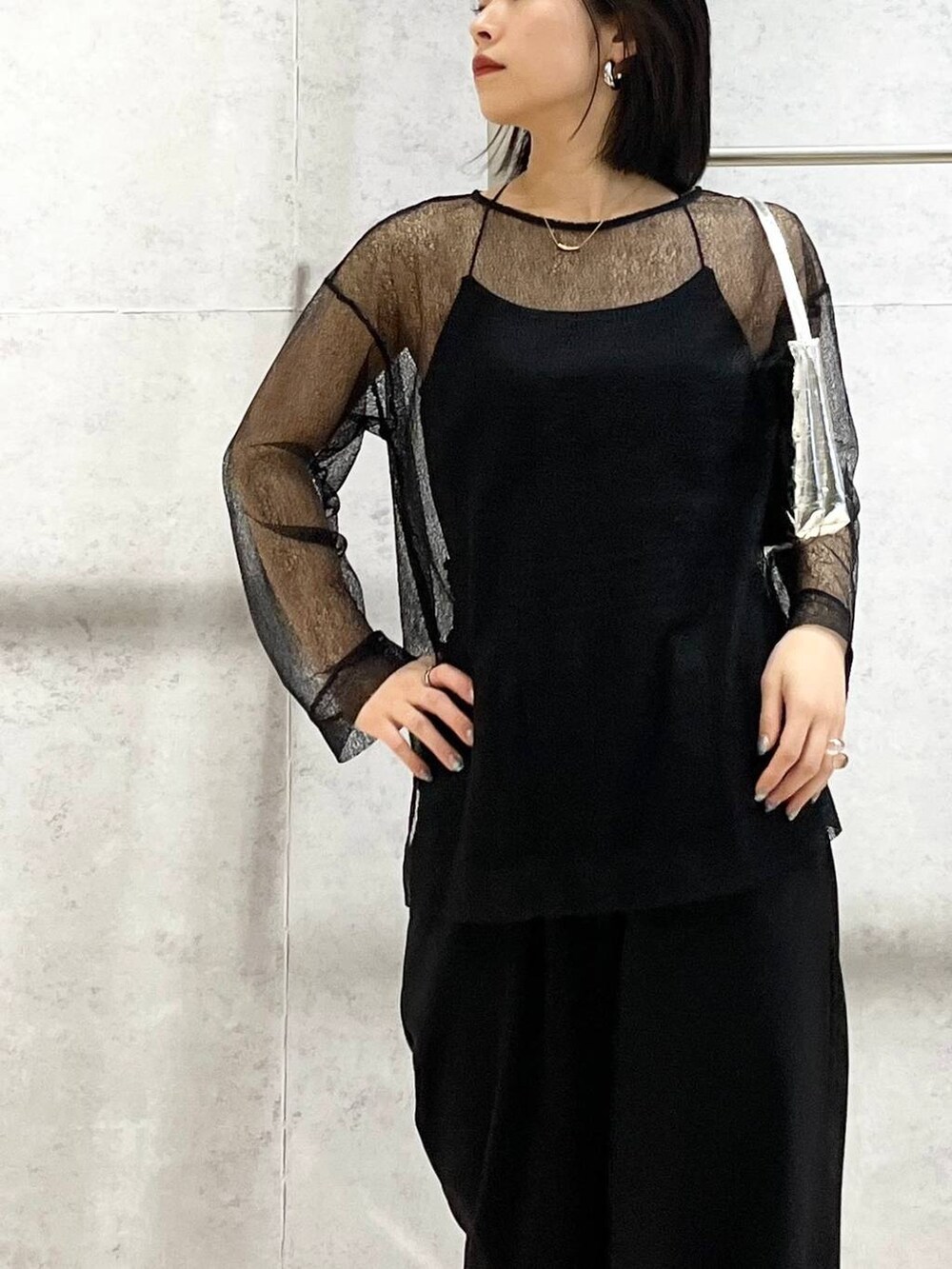 シルバー系のハンドバッグ、ブラック系のシャツ/ブラウス、ブラック系のスラックスを着用したレディースの冬コーディネートの4枚目の写真