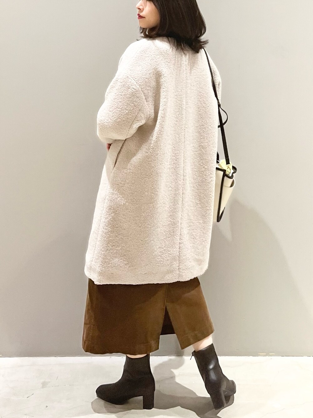 ブラック系のブーツ、ブラウン系のスカート、ホワイト系のショルダーバッグを着用したレディースの秋コーディネートの4枚目の写真