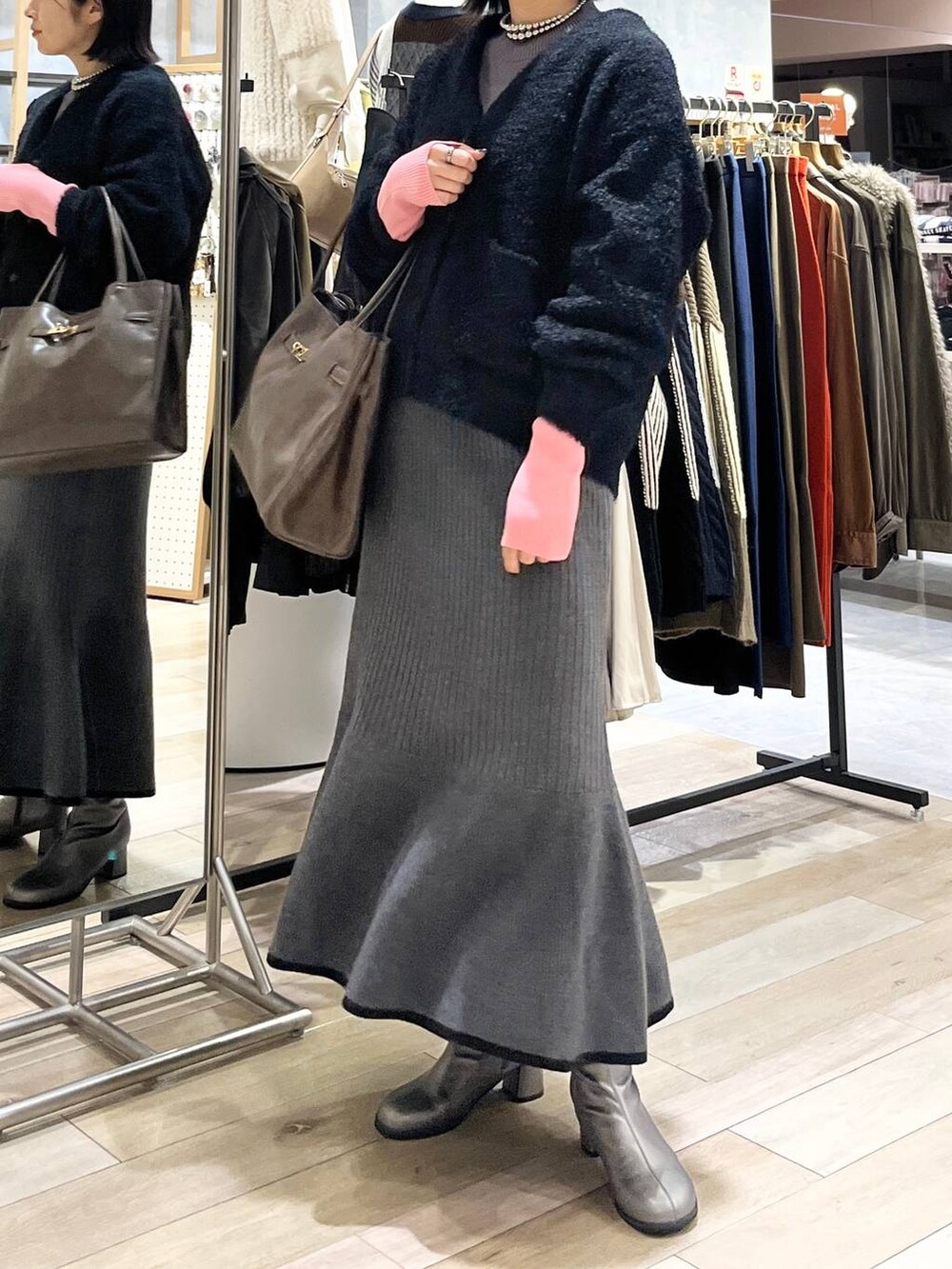 グレー系のニット/セーター、ブラック系のスカート、ブラウン系のトートバッグを着用したレディースの秋コーディネートの3枚目の写真