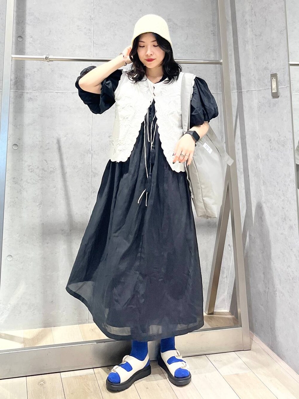 ブラック系のワンピース、ホワイト系のサンダル、ホワイト系のベストを着用したレディースの春コーディネートの7枚目の写真