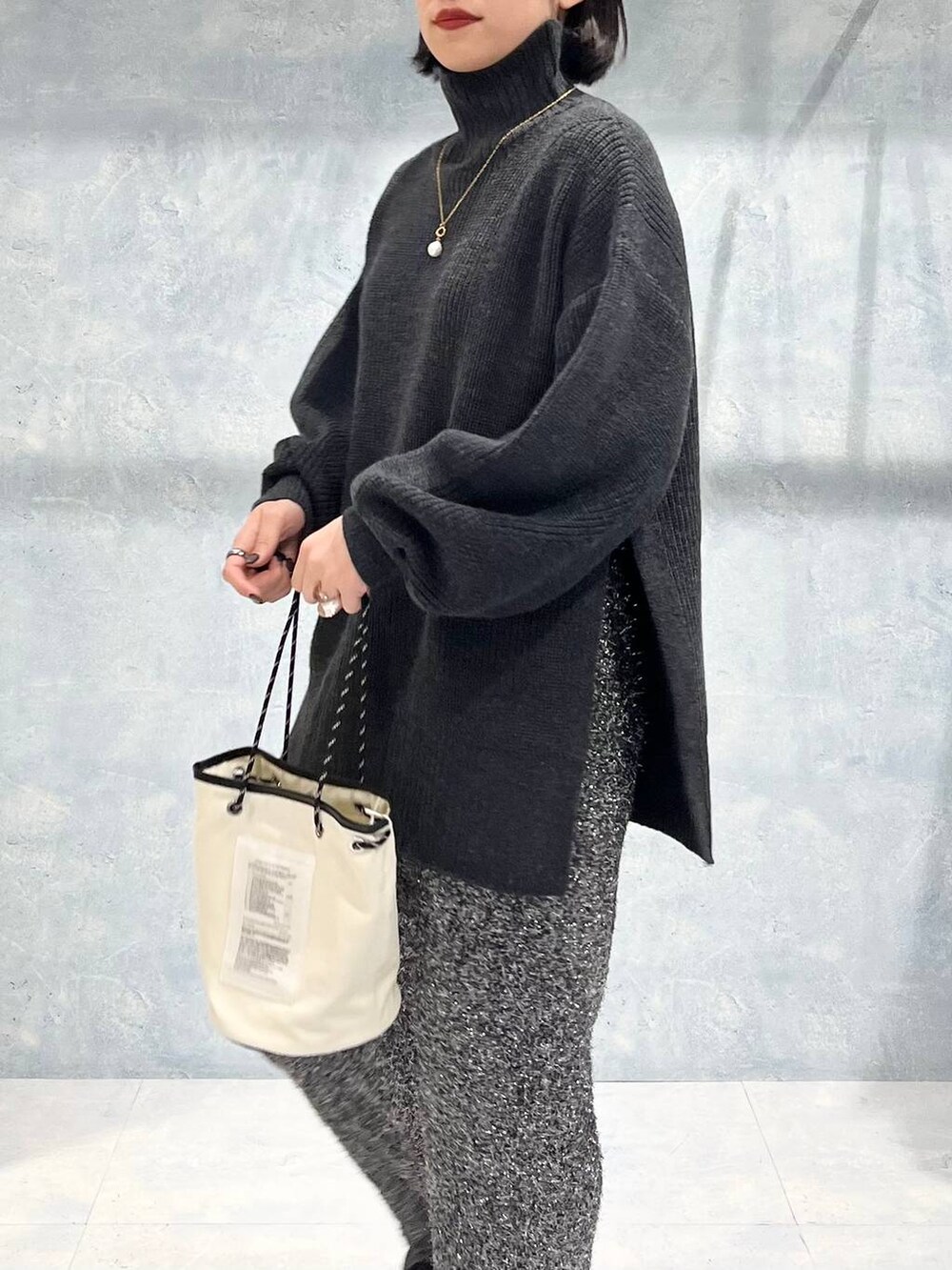 グレー系のTシャツ/カットソー、ブラック系のブーツ、ブラック系のスカートを着用したレディースの冬コーディネートの4枚目の写真