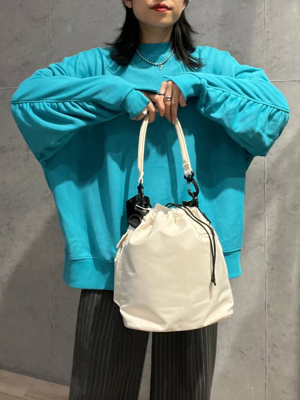 ホワイト系のショルダーバッグ、グレー系のその他パンツ、ブラック系のスニーカーを着用したレディースの冬コーディネートの2枚目の写真