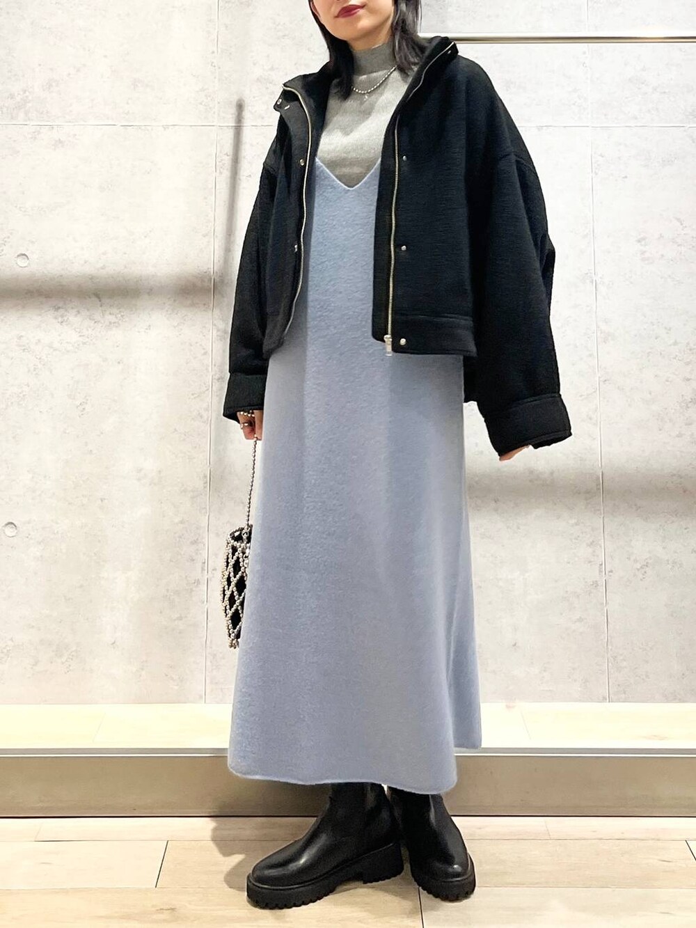 ブラック系のブルゾン、ブルー系のワンピース、ブラック系のブーツを着用したレディースの秋コーディネートの6枚目の写真