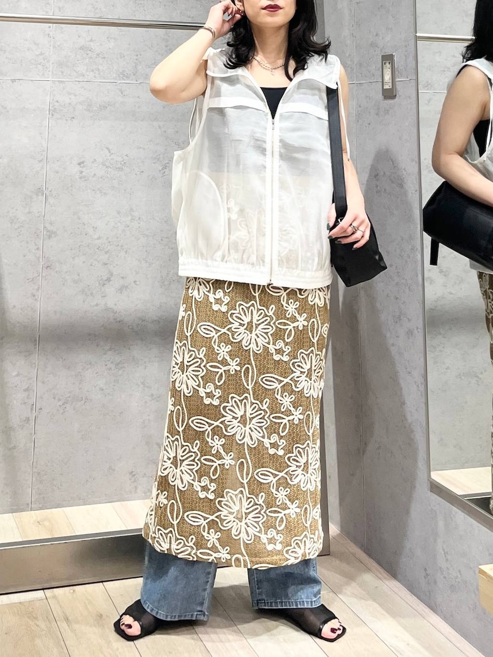 ブラック系のショルダーバッグ、ブルー系のデニムパンツ、ブラック系のサンダルを着用したレディースの春コーディネートの5枚目の写真