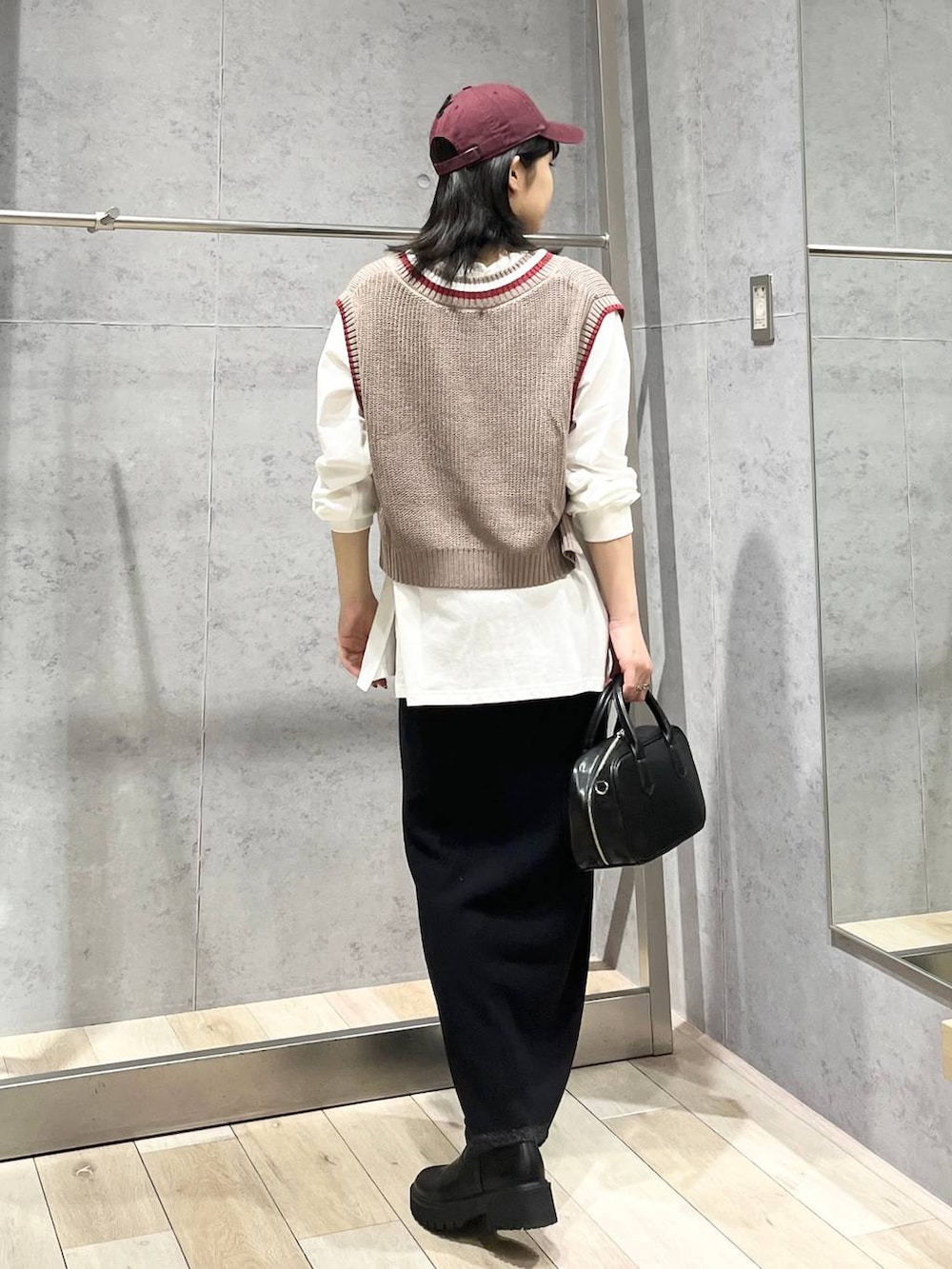 ブラック系のボストンバッグ、ブラック系のブーツ、ブラック系のスカートを着用したレディースの秋コーディネートの4枚目の写真