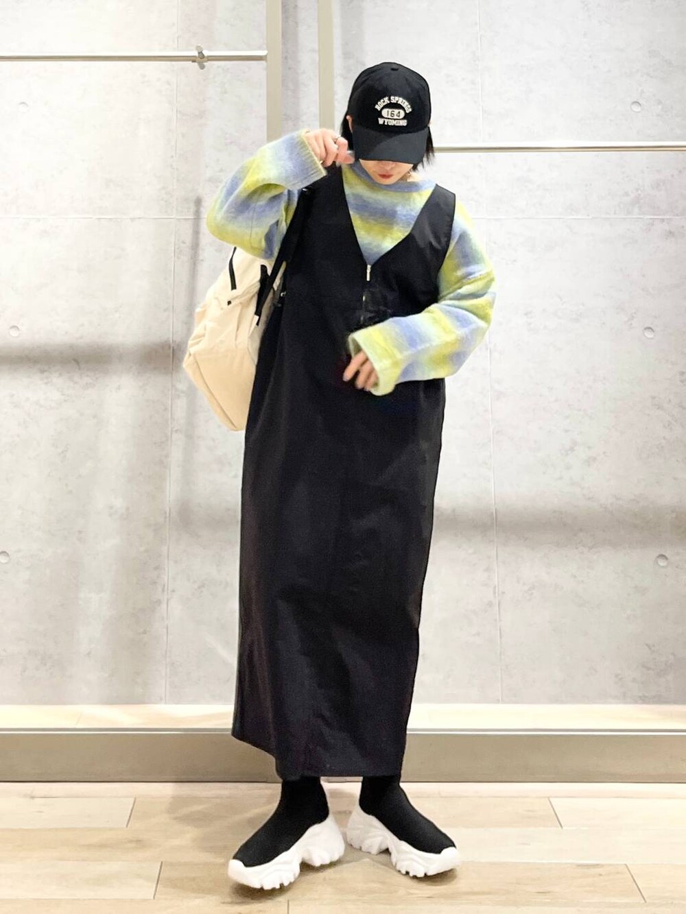 ホワイト系のバックパック/リュック、ブラック系のブーツ、ブラック系のジャンパースカートを着用したレディースの冬コーディネートの8枚目の写真