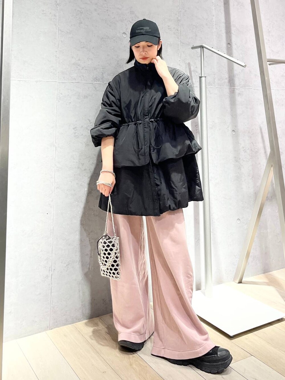 シルバー系のショルダーバッグ、ピンク系のスウェットパンツ、ブラック系のキャップを着用したレディースの秋コーディネートの7枚目の写真