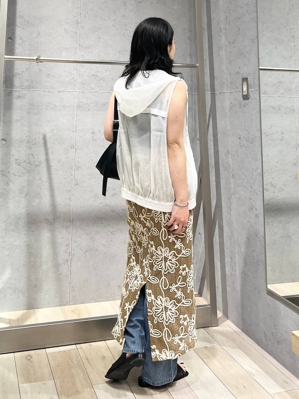 ブラック系のショルダーバッグ、ブルー系のデニムパンツ、ブラック系のサンダルを着用したレディースの春コーディネートの3枚目の写真