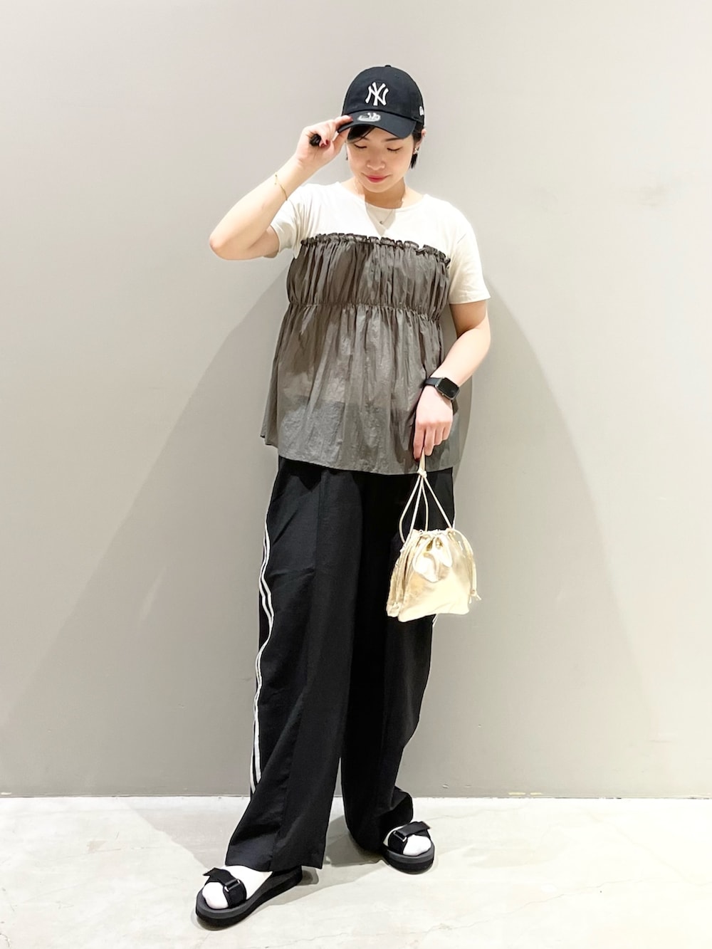 ブラック系のパンツ、ブラック系のサンダル、ゴールド系のハンドバッグを着用したレディースの秋コーディネートの2枚目の写真