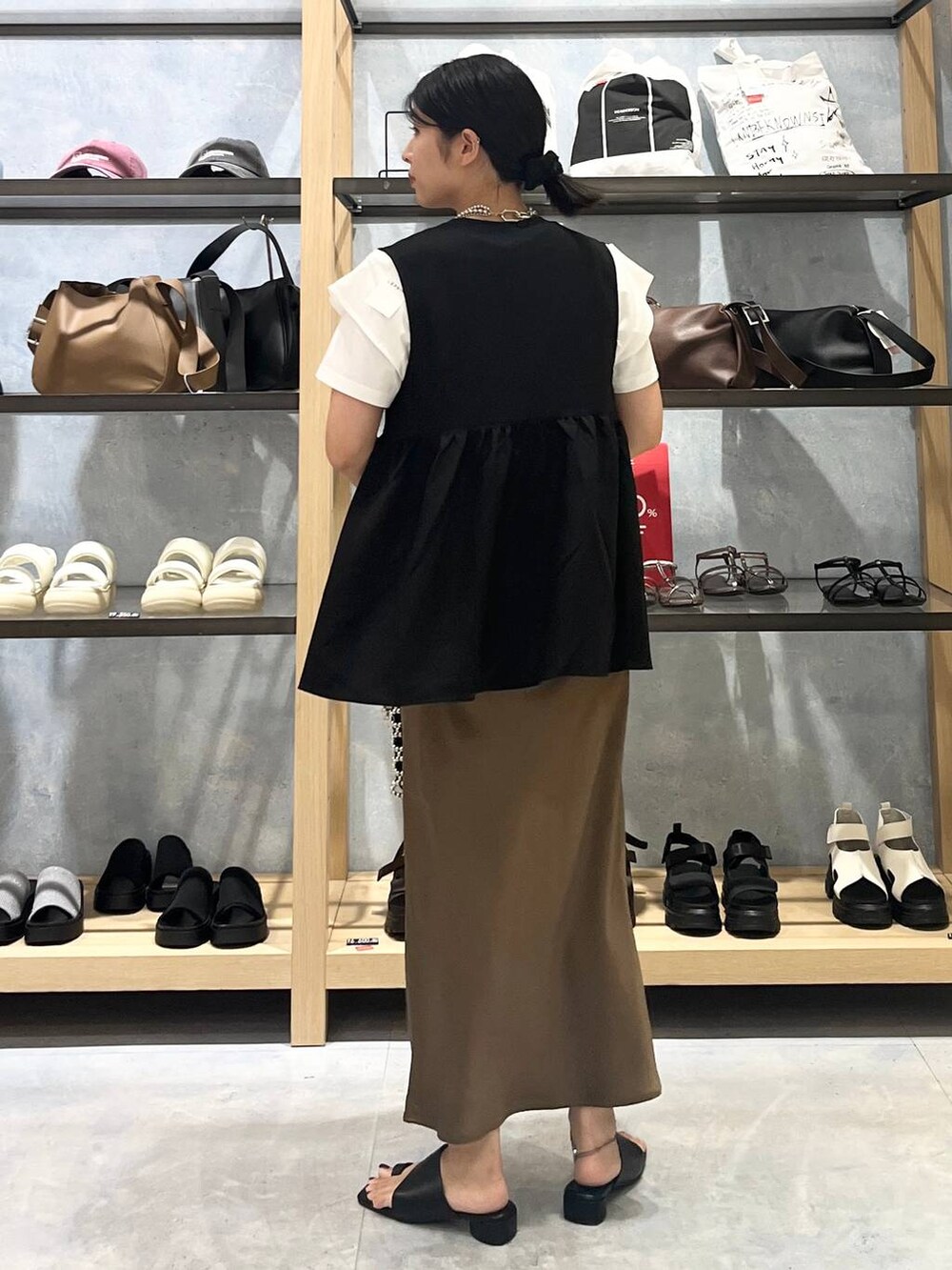 シルバー系のショルダーバッグ、ブラウン系のスカート、ブラック系のサンダルを着用したレディースの夏コーディネートの4枚目の写真