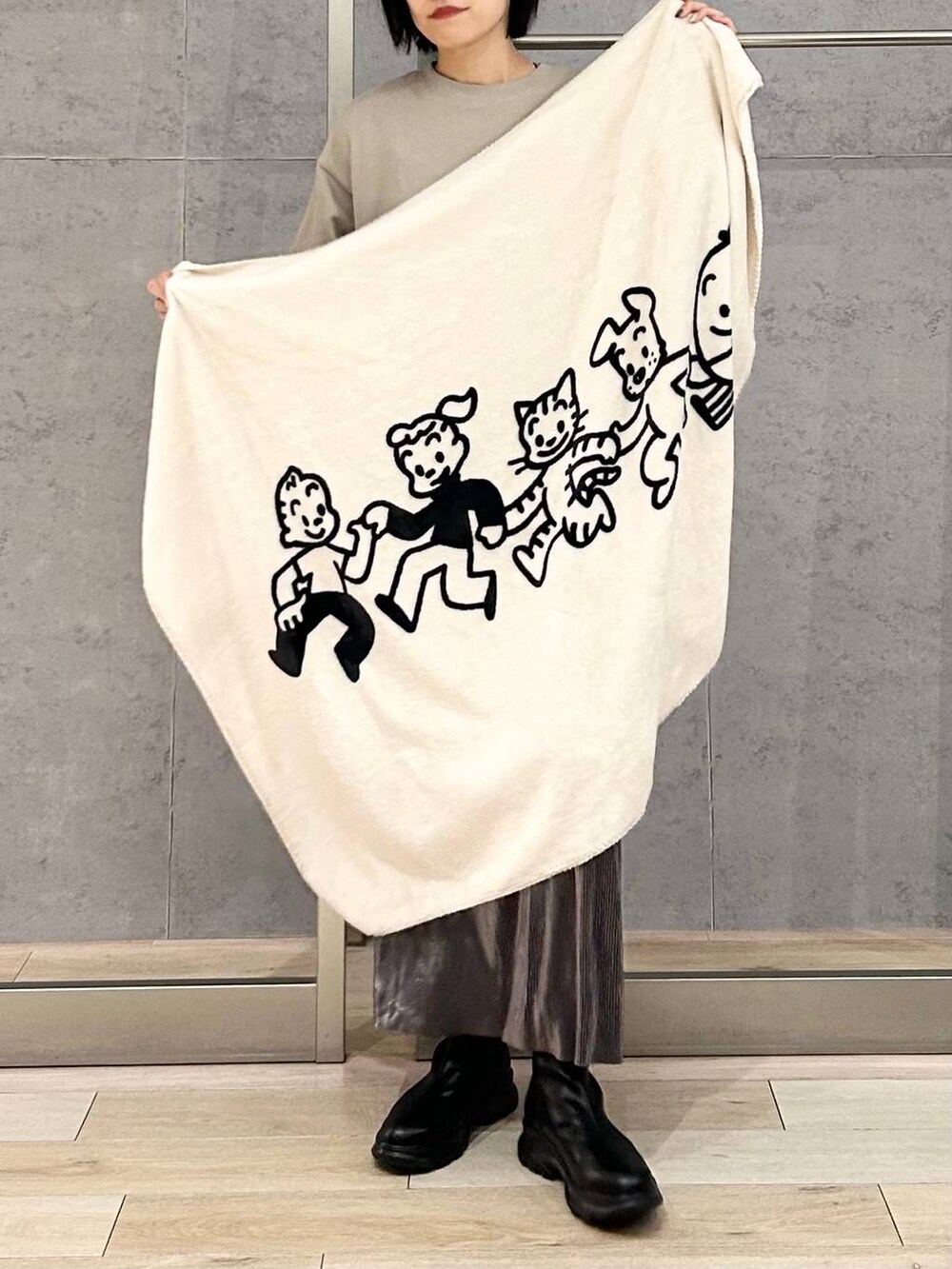 シルバー系のスカート、ブラック系のブーツ、ベージュ系のスウェットを着用したレディースの秋コーディネートの3枚目の写真