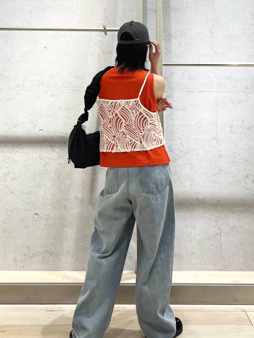 オレンジ系のタンクトップ、ブラック系のショルダーバッグ、ブルー系のデニムパンツを着用したレディースの夏コーディネートの6枚目の写真