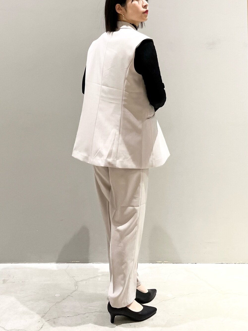 ブラック系のパンプス、ベージュ系のスラックス、ブラック系のハンドバッグを着用したレディースの冬コーディネートの4枚目の写真