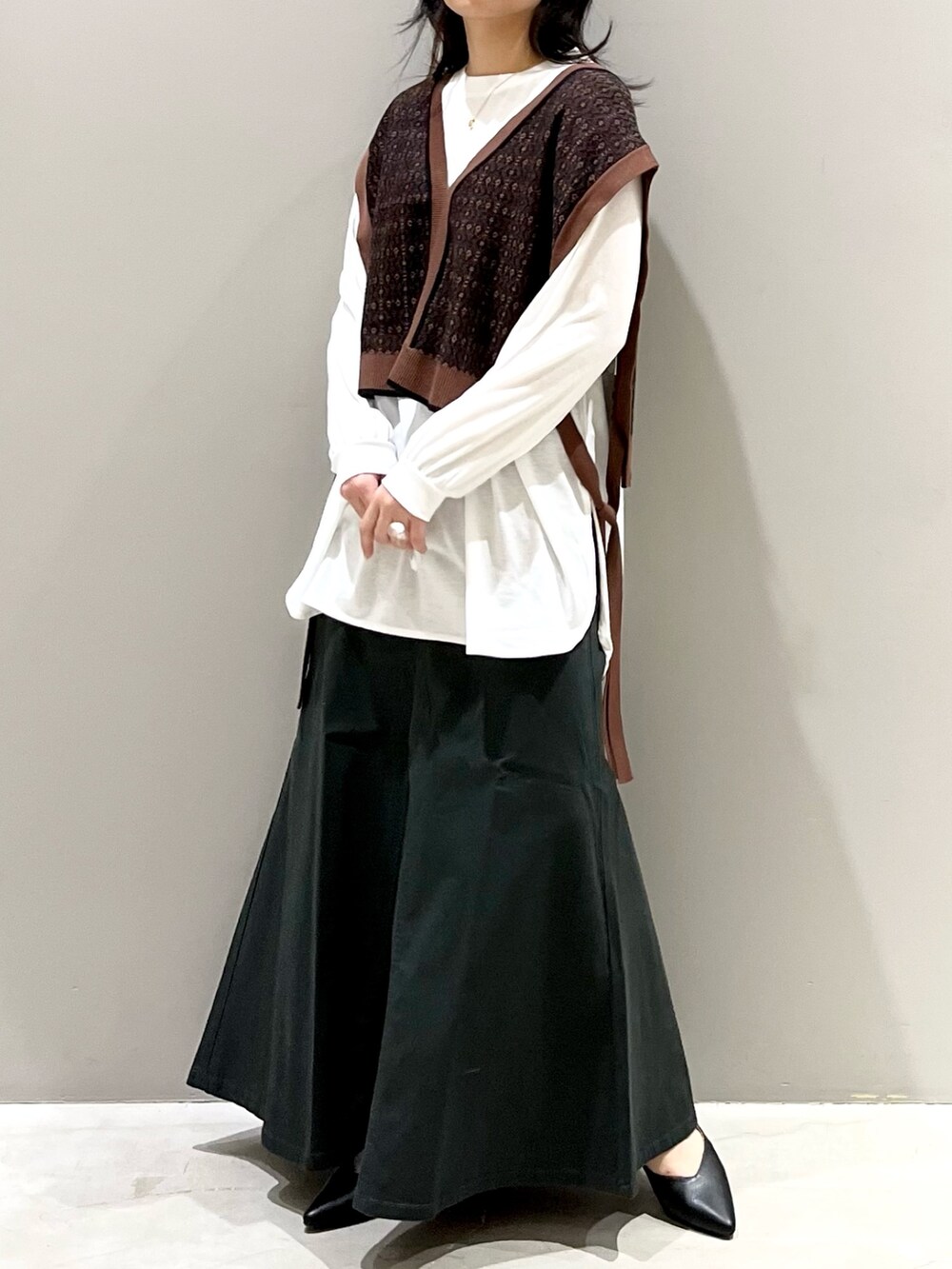 グレー系のスカート、ブラック系のパンプス、ブラウン系のマタニティウェア/グッズを着用したレディースの秋コーディネートの4枚目の写真