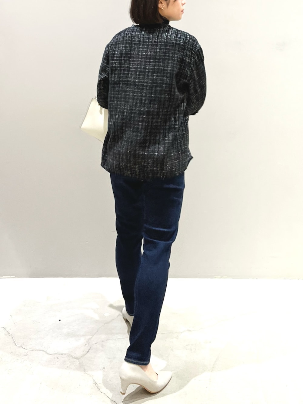 ホワイト系のショルダーバッグ、ベージュ系のパンプス、ブルー系のデニムパンツを着用したレディースの春コーディネートの4枚目の写真