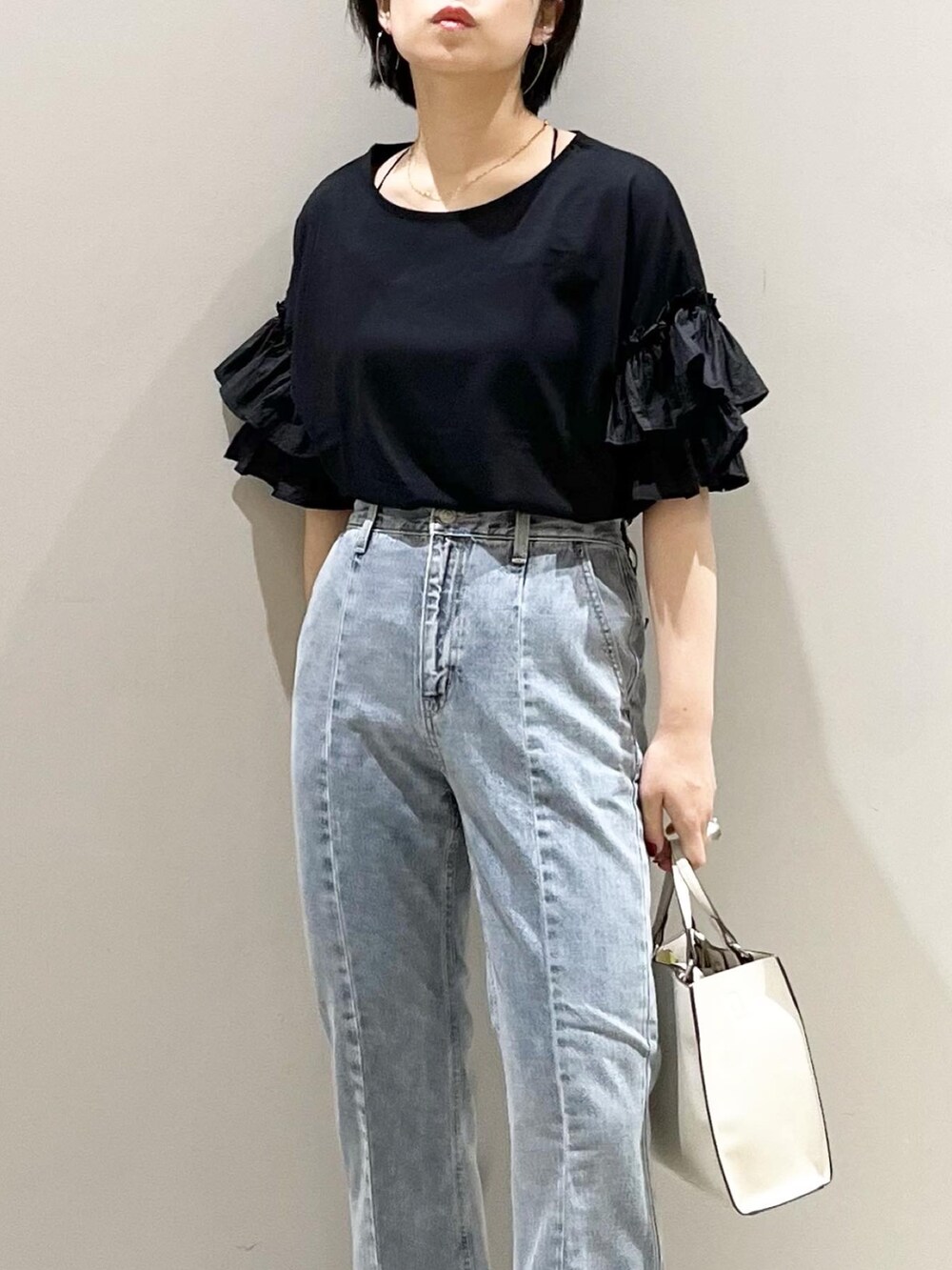 ブルー系のデニムパンツ、ホワイト系のショルダーバッグ、ホワイト系のパンプスを着用したレディースの夏コーディネートの7枚目の写真