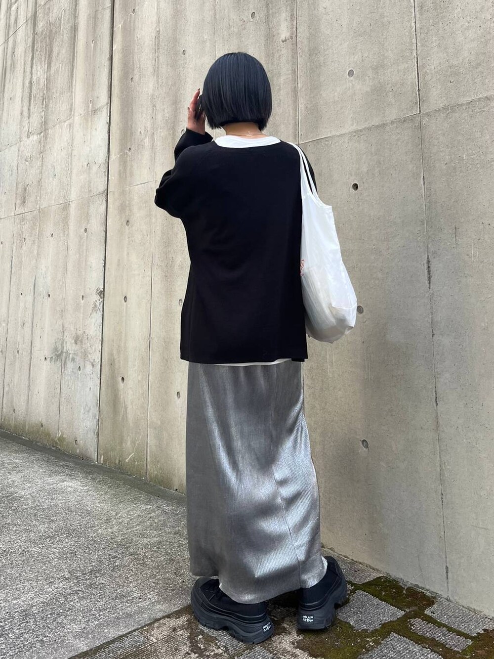 ブラック系のニット/セーター、ホワイト系のTシャツ/カットソー、シルバー系のスカートを着用したレディースの秋コーディネートの6枚目の写真