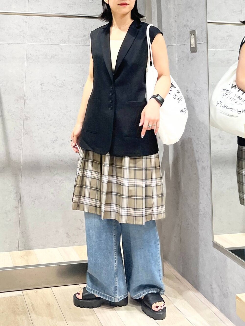 ホワイト系のタンクトップ、ブラック系のサンダル、ベージュ系のスカートを着用したレディースの秋コーディネートの5枚目の写真