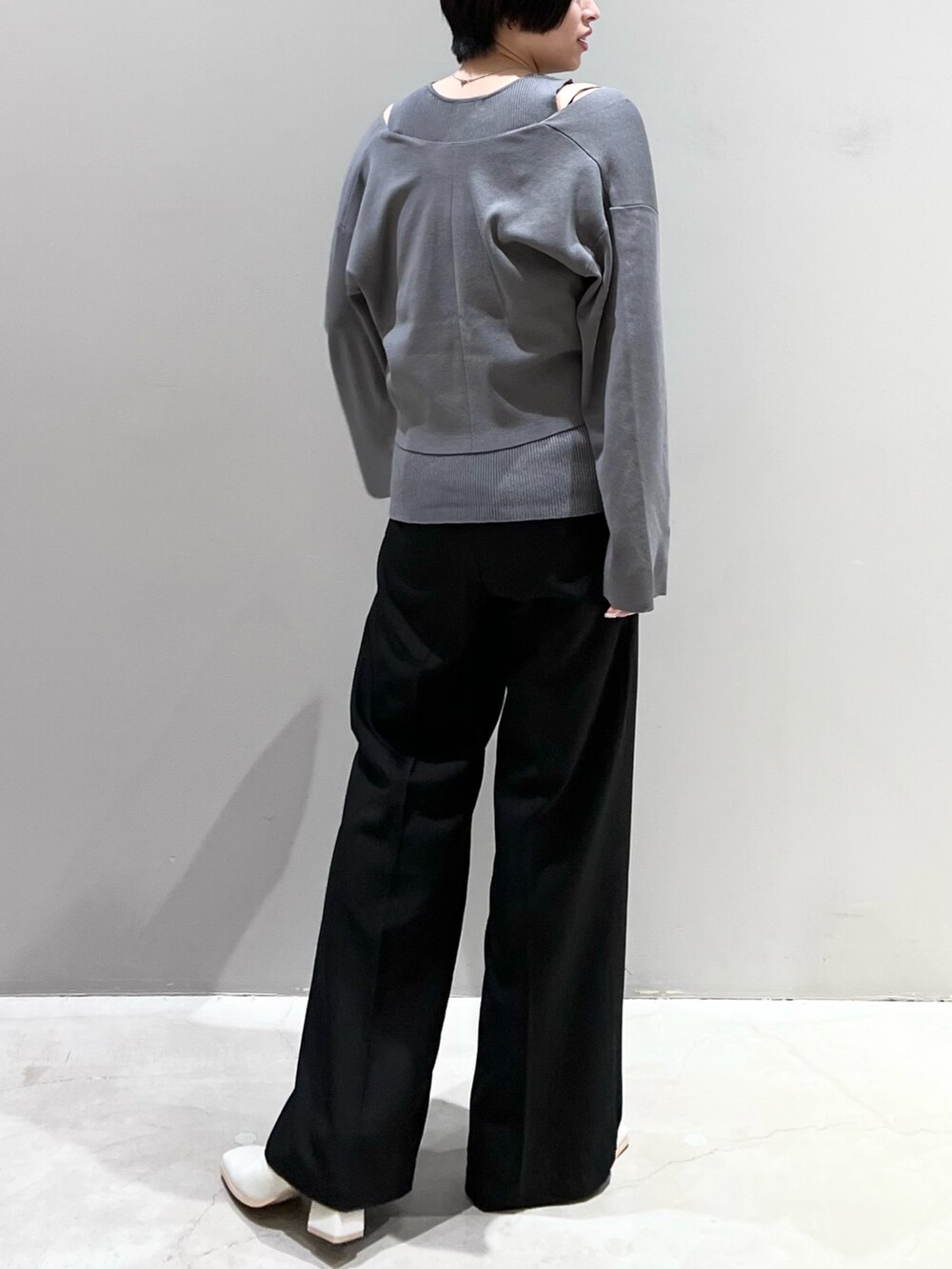 グレー系のニット/セーター、ブラック系のパンツ、ホワイト系のシューズを着用したレディースの春コーディネートの6枚目の写真