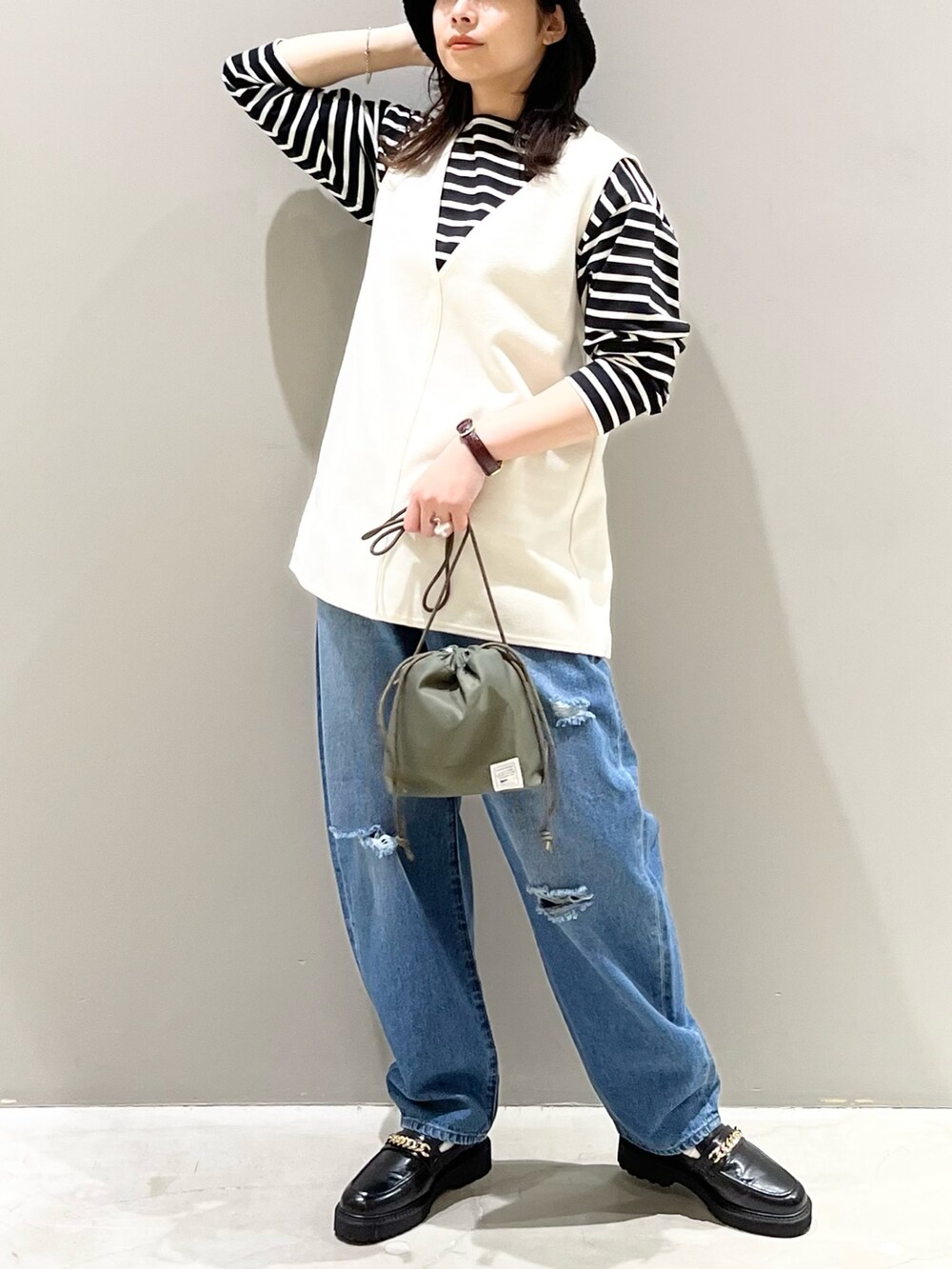 ブルー系のデニムパンツ、ブラック系のローファー、グリーン系のショルダーバッグを着用したレディースの冬コーディネートの5枚目の写真