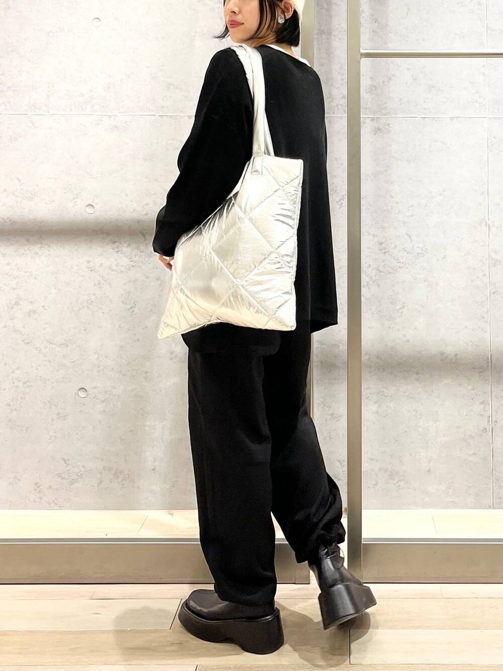 ブラック系のニット/セーター、ホワイト系のTシャツ/カットソー、ブラック系のブーツを着用したレディースの秋コーディネートの6枚目の写真