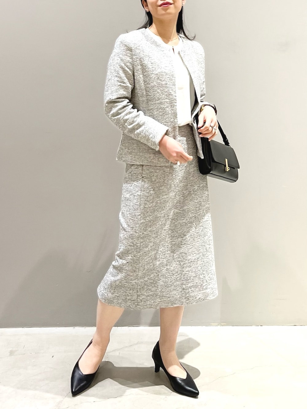 ブラック系のパンプス、ホワイト系のスーツスカート、ホワイト系のシャツ/ブラウスを着用したレディースの冬コーディネートの3枚目の写真