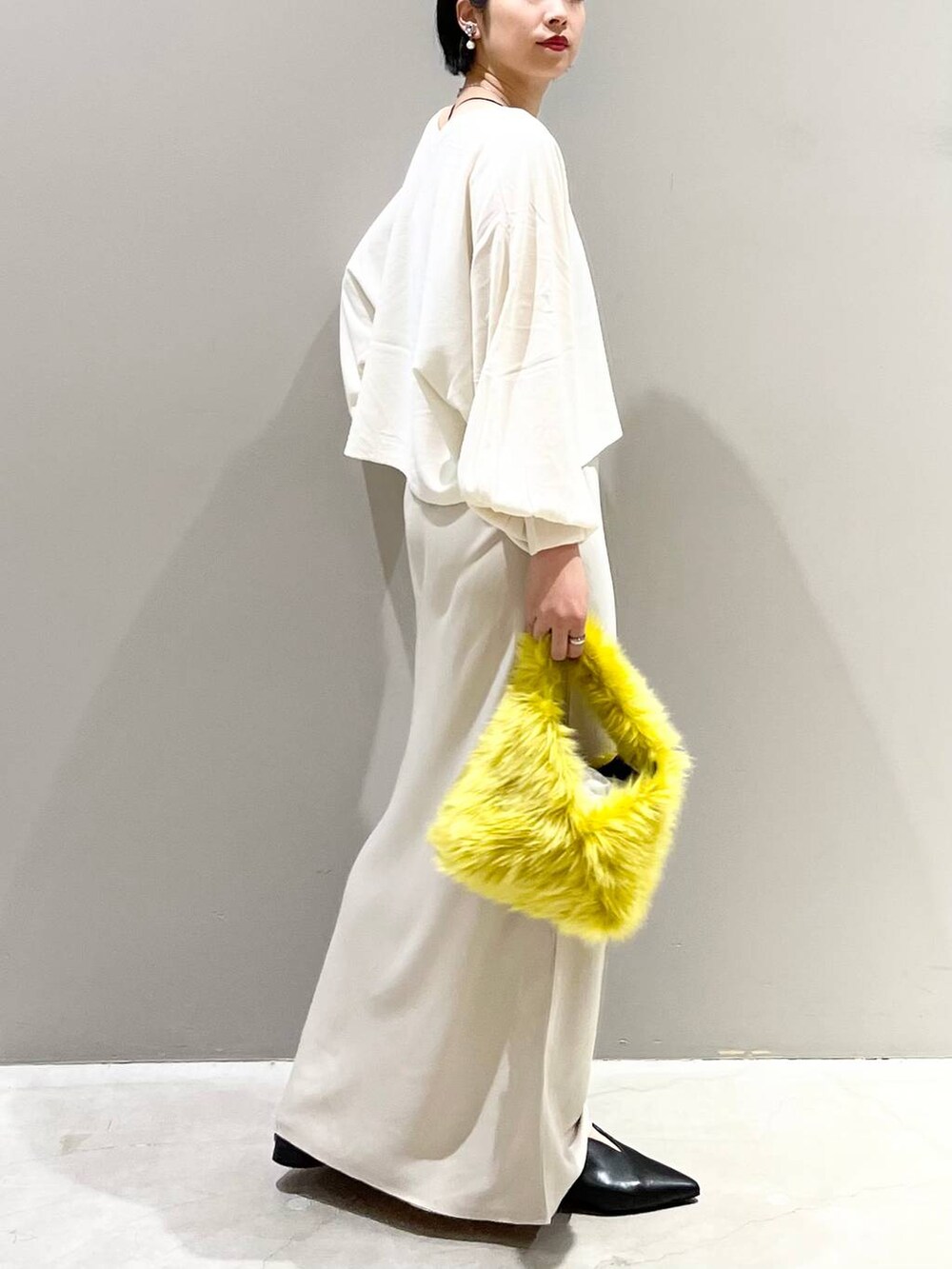 ブラック系のキャミソール、ホワイト系のニット/セーター、イエロー系のハンドバッグを着用したレディースの秋コーディネートの5枚目の写真