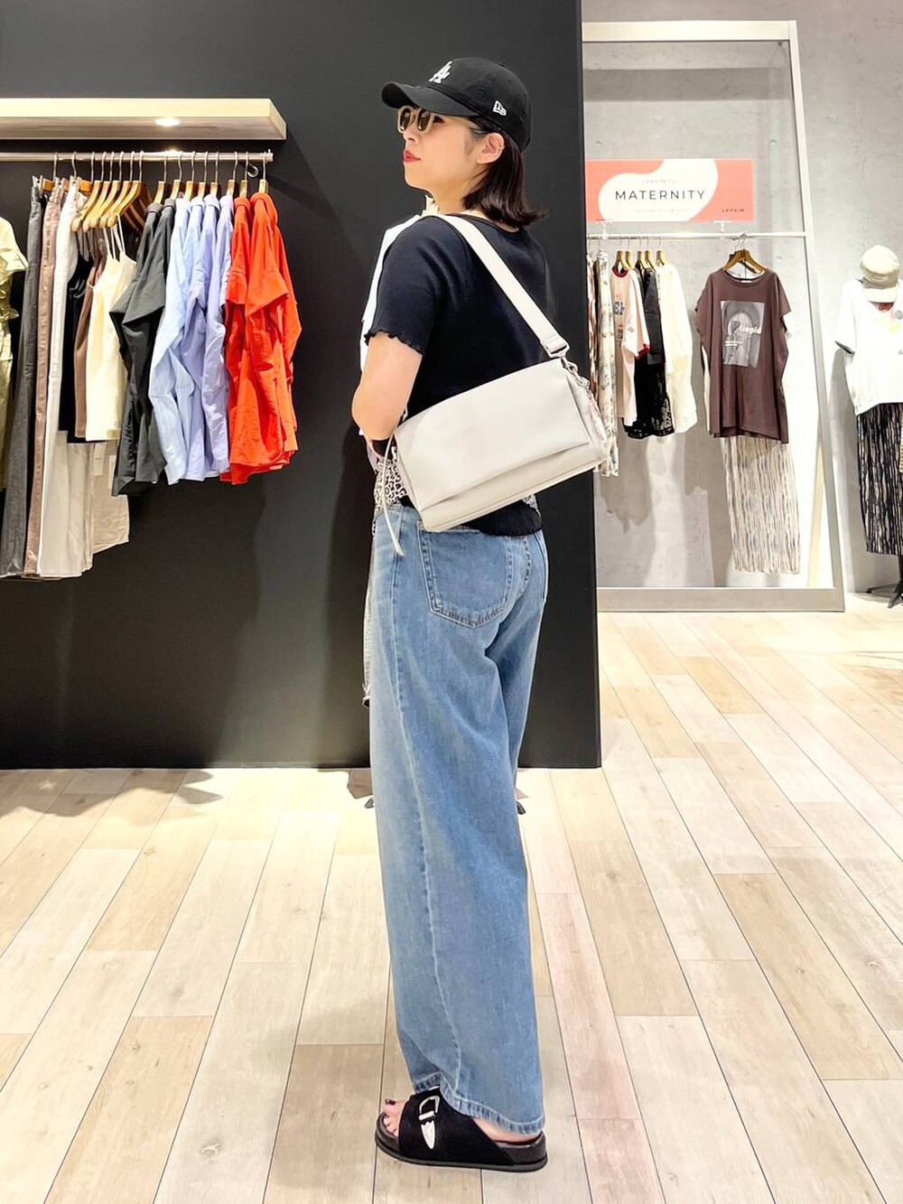 ブラック系のサンダル、ブルー系のデニムパンツ、グレー系のショルダーバッグを着用したレディースの夏コーディネートの5枚目の写真