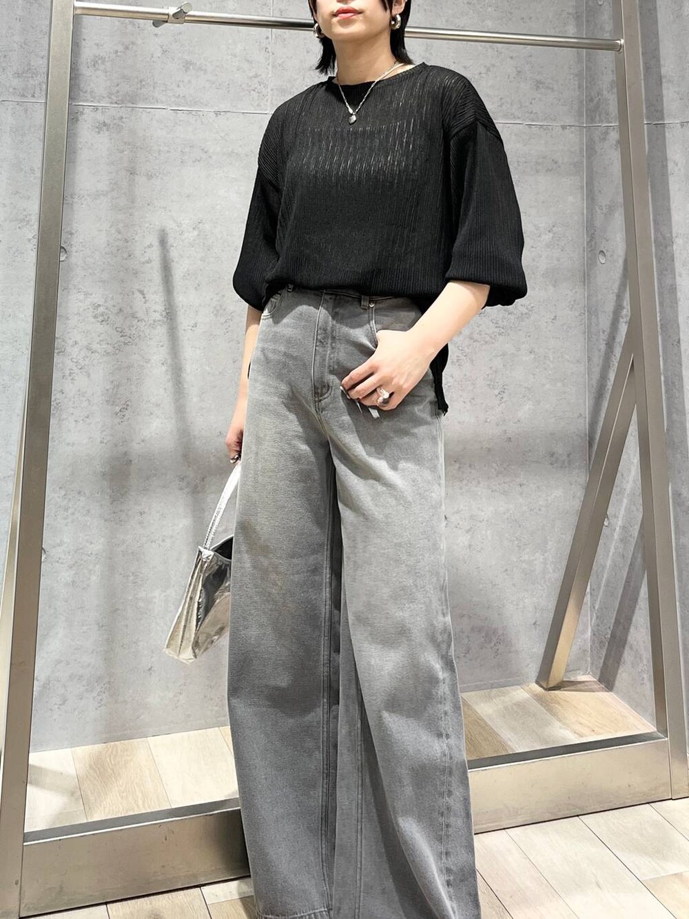 シルバー系のハンドバッグ、ブラック系のサンダル、グレー系のデニムパンツを着用したレディースの春コーディネートの5枚目の写真