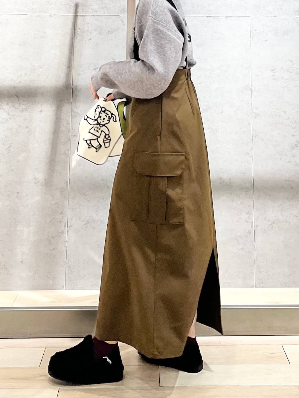 ブラック系のモカシン/デッキシューズ、ブラウン系のスカート、グレー系のニット/セーターを着用したレディースの冬コーディネートの4枚目の写真