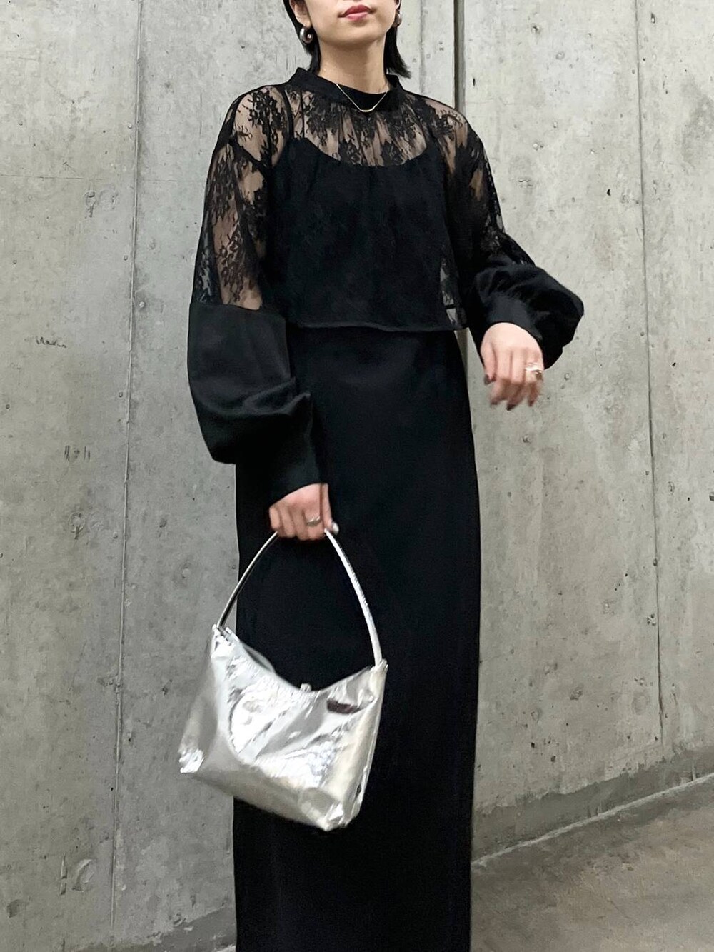 シルバー系のハンドバッグ、ホワイト系のパンプス、ゴールド系のネックレスを着用したレディースの春コーディネートの3枚目の写真