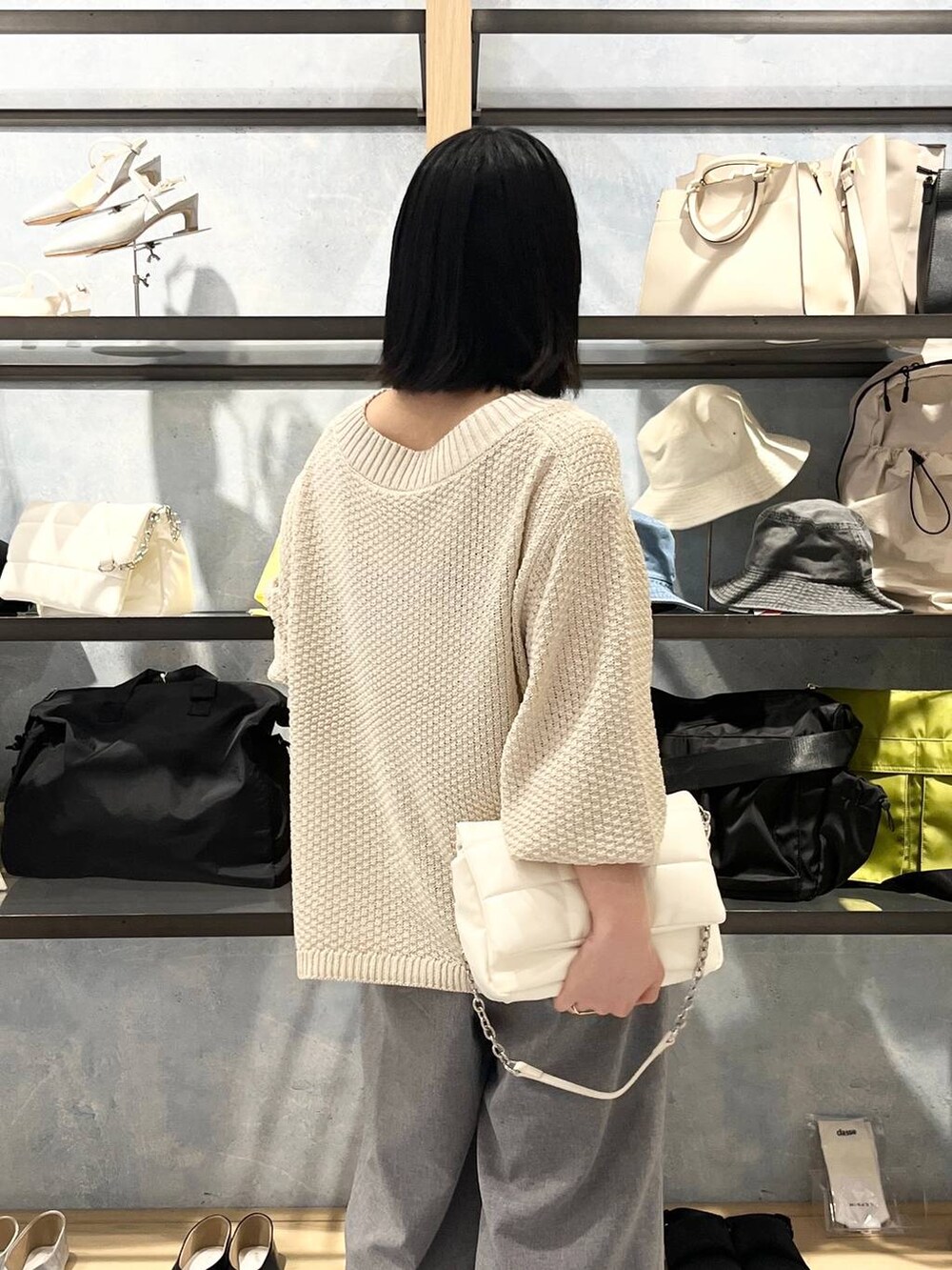 ホワイト系のショルダーバッグ、ホワイト系のニット/セーター、グレー系のスラックスを着用したレディースの春コーディネートの5枚目の写真